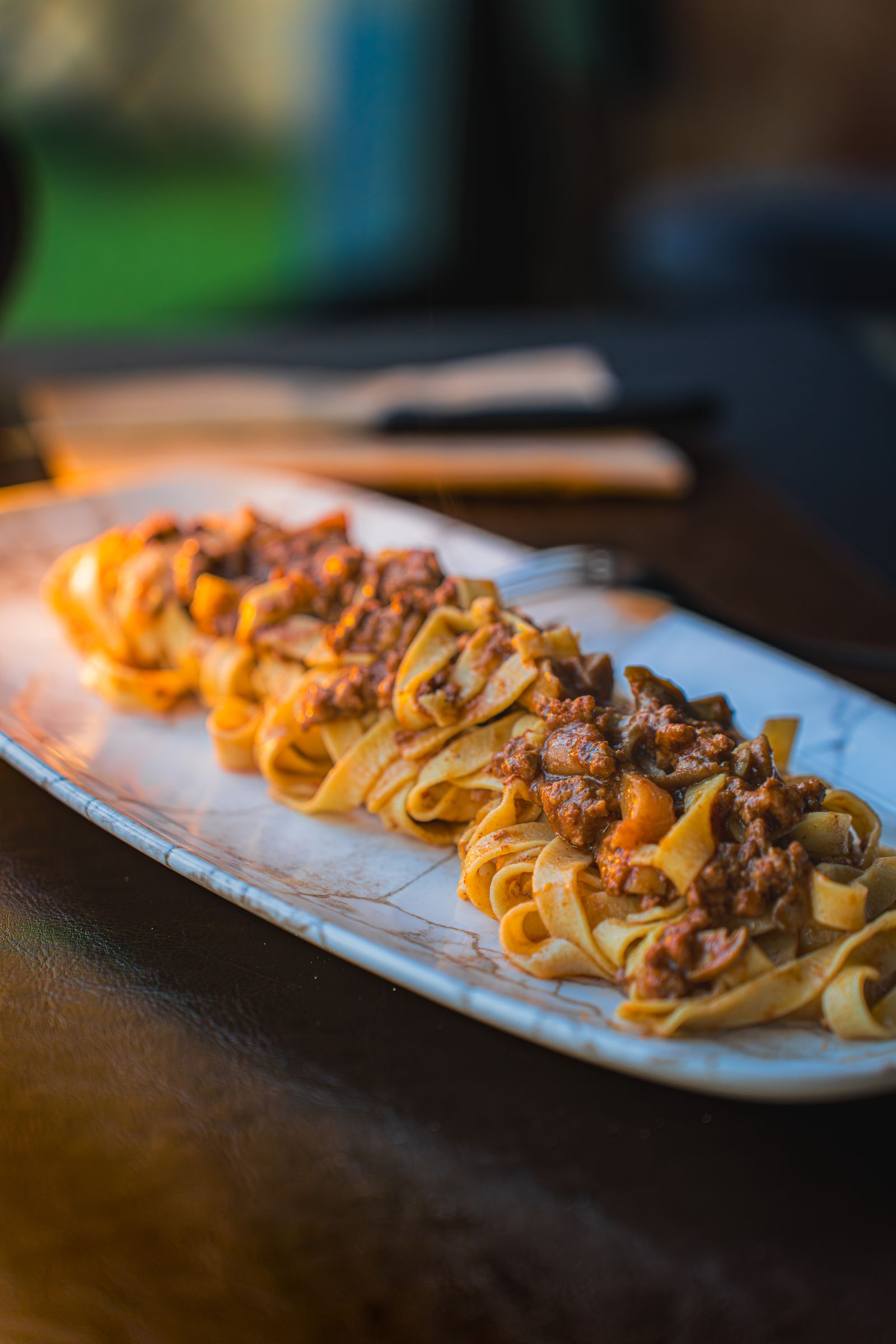 Pappardelle all'uovo con ragù di carne su un piatto da portata in ceramica
